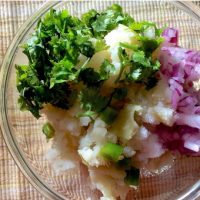 A bowl of mashed potato, coriander leaves, salt and onions for stuffed shimla mirch