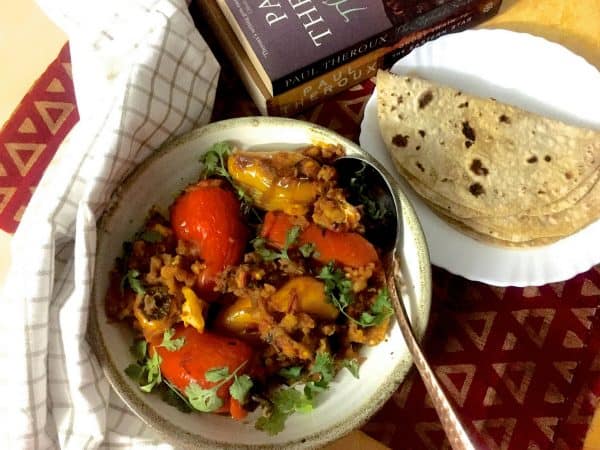 Stuffed Capsicum Peppers_F A round plate of stuffed Shimla mirch or coloured bell peppers stuffed with potato mash with a plate of chapatis, books and a checked napkin on the side