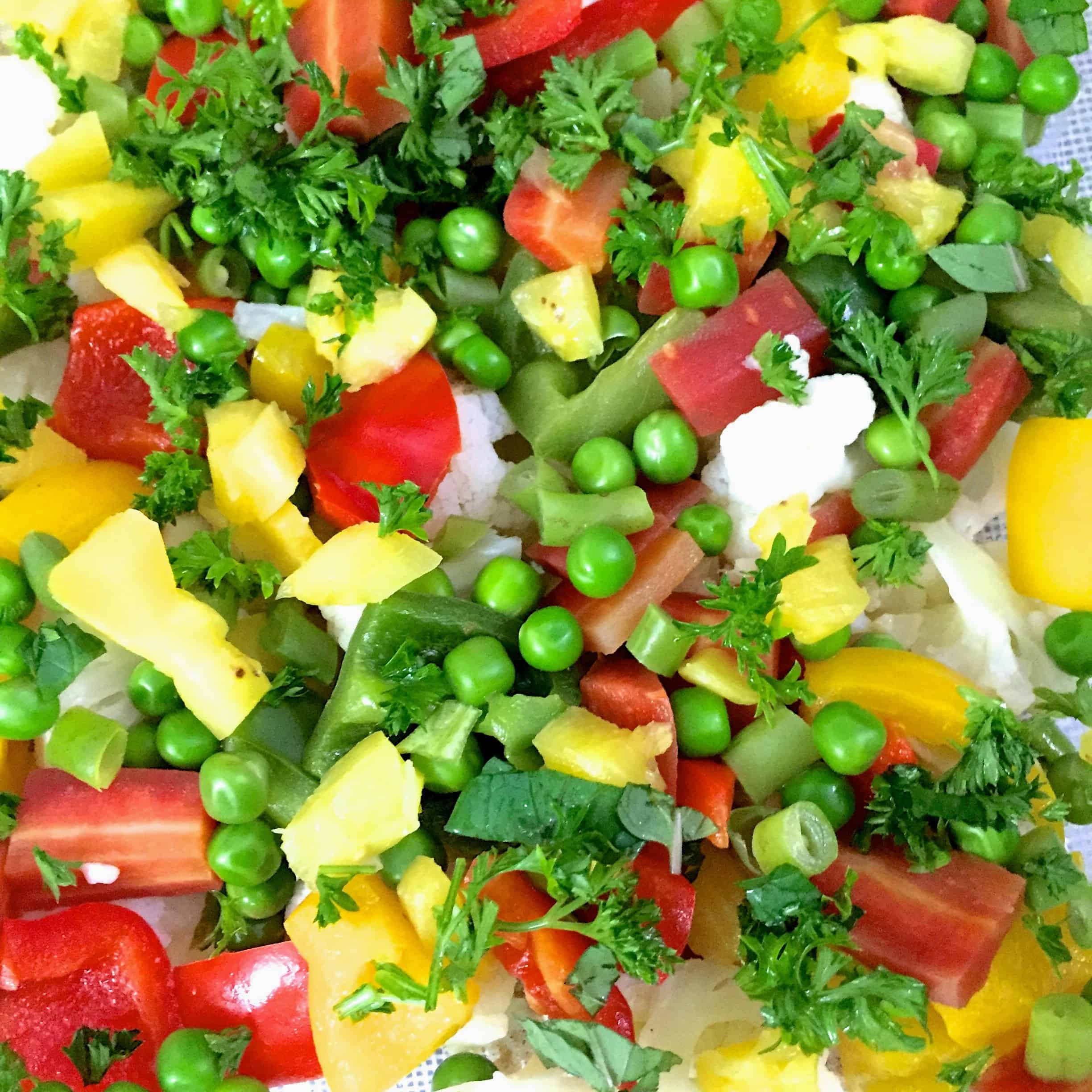 Brightly coloured green, red, yellow and white slices of vegetables in a baking dish, ready to bake