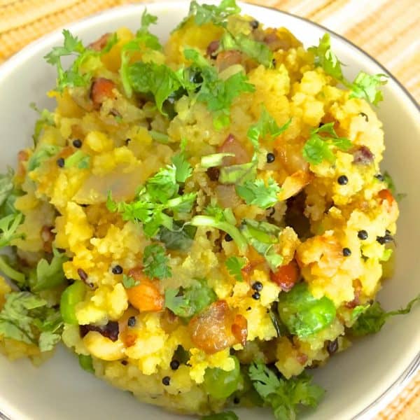 Poha A bowl of bright yellow poha with peas and peanuts garnished with cilantro and tempered with mustard