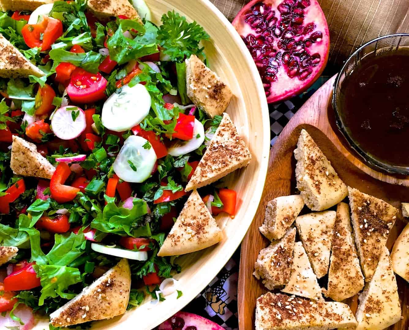 A plate of Fattoush Lebanese bread salad with traditional ingredients sumac, za'atar with pita bread, radish, tomato, greens and pomegranate molasses