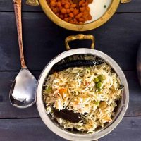 Matar ki Tehari from Eastern UP in India. A Pot of rice and peas cooked in spices, with a bowl of raita and a spoon alongside