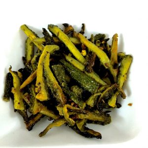 Overhead view of strips of green bitter gourd or karela, after frying with turmeric and salt