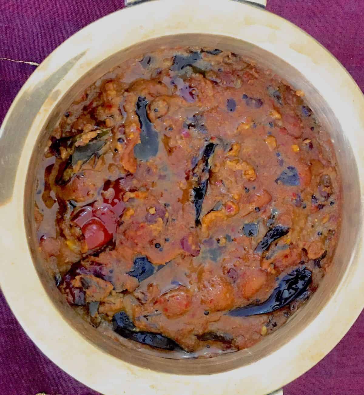 Pulikachal to make Puliyodharai, a dark brown tamarind paste cooked in spices and oil with chilies, in a round bowl seen from overhead