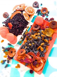 A variety of dry fruits for soaking for a Christmas cake, on an orange plate with a blue and white backgroun