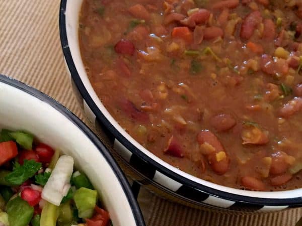 Rajma Masala Curry Flavourful Nutritious Rajma Masala Curry of red kidney beans in a thick tomato onion gravy in checkered black and white bowl with salad by the side