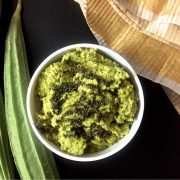 Pathiya Peerkangai Thogayal, a green chutney, in a small bowl. Ridge gourd seen on the left, a green and white napkin on the side