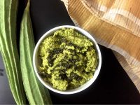 Pathiya Peerkangai Thogayal, a green chutney, in a small bowl. Ridge gourd seen on the left, a green and white napkin on the side