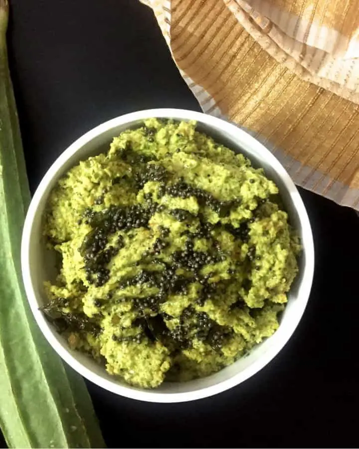 Pathiya Peerkangai Thogayal, a green chutney, in a small bowl. Ridge gourd seen on the left, a green and white napkin on the side