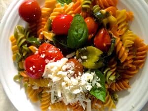 Colourful burst cherry tomatoes with coloured rotini pasta 