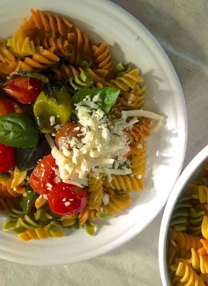 Colourful Rotini Pasta from juicy cherry tomatoes, garlic, fresh basil and spirally wholewheat pasta, on a white plate