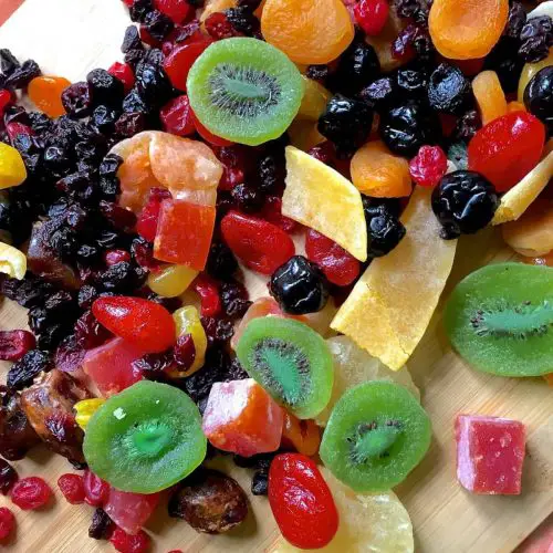 A colourful array of dry fruits, kiwi, pineapple, berries, citrus, papaya ready to be cut to soak fruits for Christmas cake