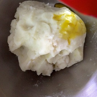 Yellow mustard oil added to mashed potatoes from a red container