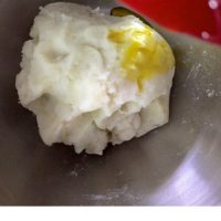 Mustard oil being added to mashed potatoes from a red spoon