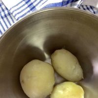 3 small potatoes, boiled and peeled , in a bowl with a blue checked cloth on one side