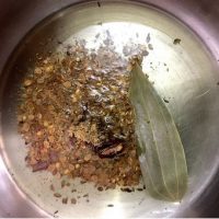 Bay leaf and spices sautéed in oil for making Split Urad dal vadi in Spinach gravy