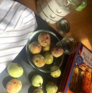 Ingredients for Homemade Fig Jam with mint -fresh figs, sugar and a recipe book with a white and pale brown striped napkin on one side