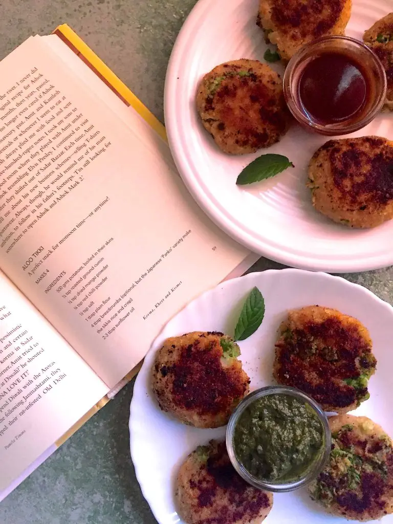 Two white plates of aloo Tikki (potato patties) with an open book showing the recipe from which they are prepared