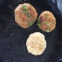 Aloo Tikki or Potato Patties being shallow fried in a little oil on a flat iron pan