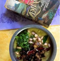 A bowl of Arhar ki Khatti Dhal on a yellow background, a mauve Lucknowi chikan saree and a novel based in Lucknow