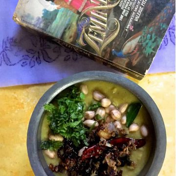 A bowl of Arhar ki Khatti Dhal on a yellow background, a mauve Lucknowi chikan saree and a novel based in Lucknow