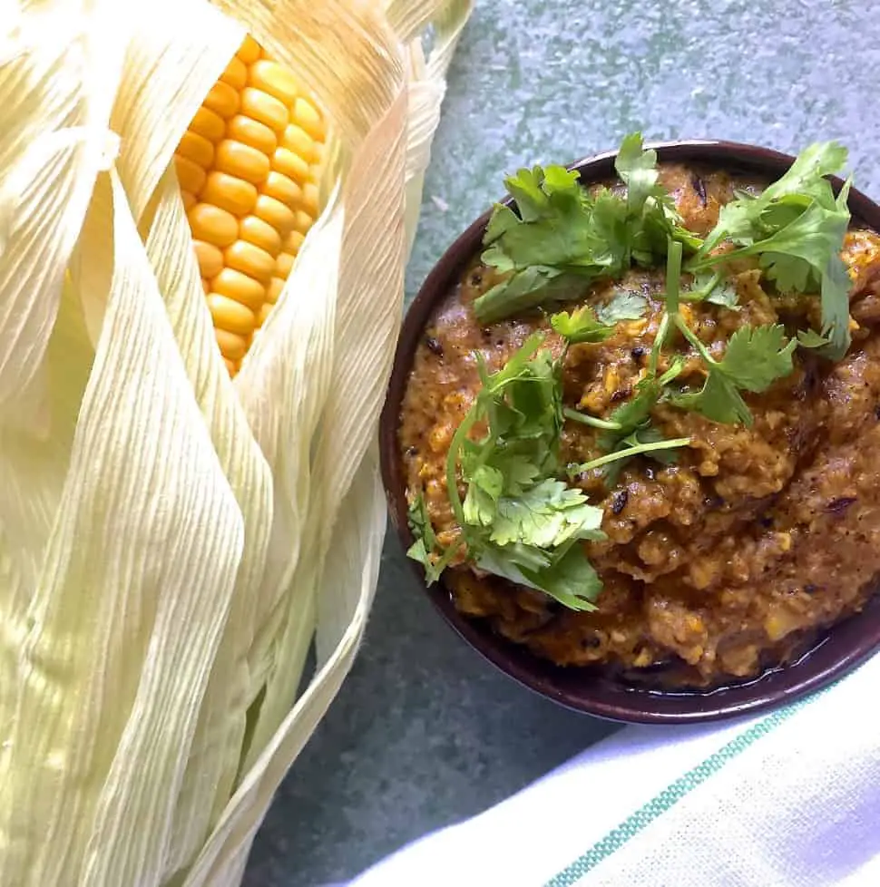 Makai ki sabzi, a spicy corn curry. Served in a bowl garnished with coriander leaves and with a corn cob on the side