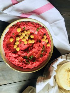 Roasted beet hummus garnished with boiled chickpeas and with pita bread