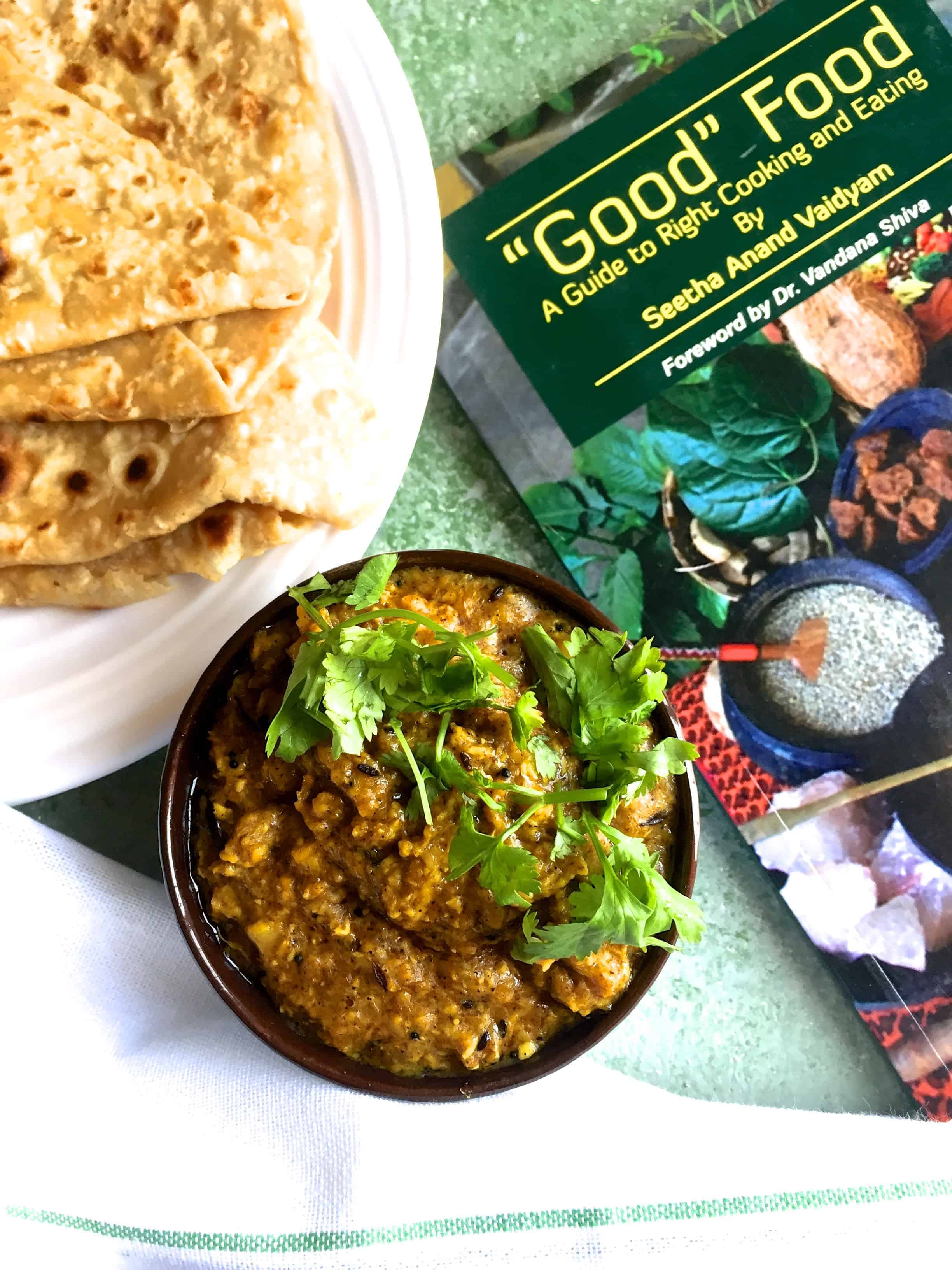 A bowl of corn curry with chapatis and with a book on Good Food alongside