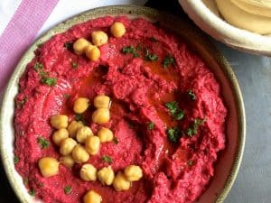 Pretty as a picture Roasted beetroot hummus garnished with cooked chickpeas and bits of parsley and with olive oil
