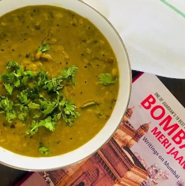 970×978 Amti Dal Comfort food Maharashtrian Amti Dal with Goda Masala in a large bowl with coriander leaves garnish and a book on Mumbai alongside