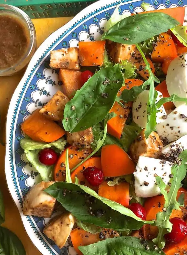 Autumn and Winter goodness of Persimmon and fresh mozzarella in a salad with mustard and balsamic vinegar and basil leaves on the side