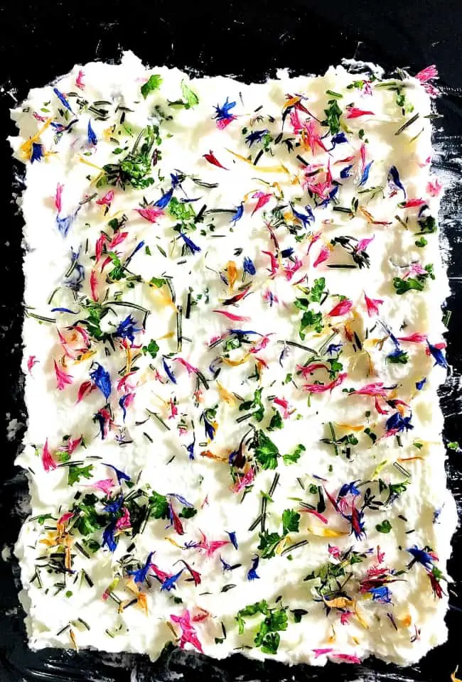 Party fare Edible Flower and Herb Butter with flowers and herbs strewn on butter for a spread or a dip