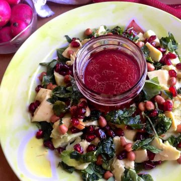 Avocado Fenugreek Leaves Salad with Peanuts, feta and pomegranate arranged on a green plate with pink dressing in the centre and reddish pink radishes in a bowl