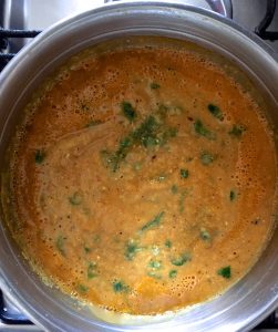 Adding shredded moringa leaves to the pureed soup