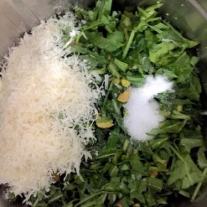 Ingredients for making arugula (rocket) leaves pesto including fresh green arugula leaves and parmesan