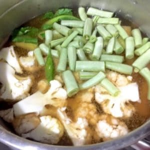 Add cauliflower stalks, florets, potatoes and beans to a pot of water, with salt