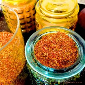 Blue yellow and orange jars with rusty orange coloured rasam powder, a homemade spice powder from Indian Tamil cuisine