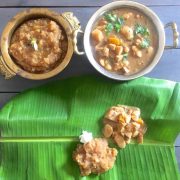 Thiruvathirai Kali, a brown coloured sweet dish, in a brass bowl and some spread on a green banana leaf. Vegetable stew in another bowl and on the leaft, with a pat of white butter by the side