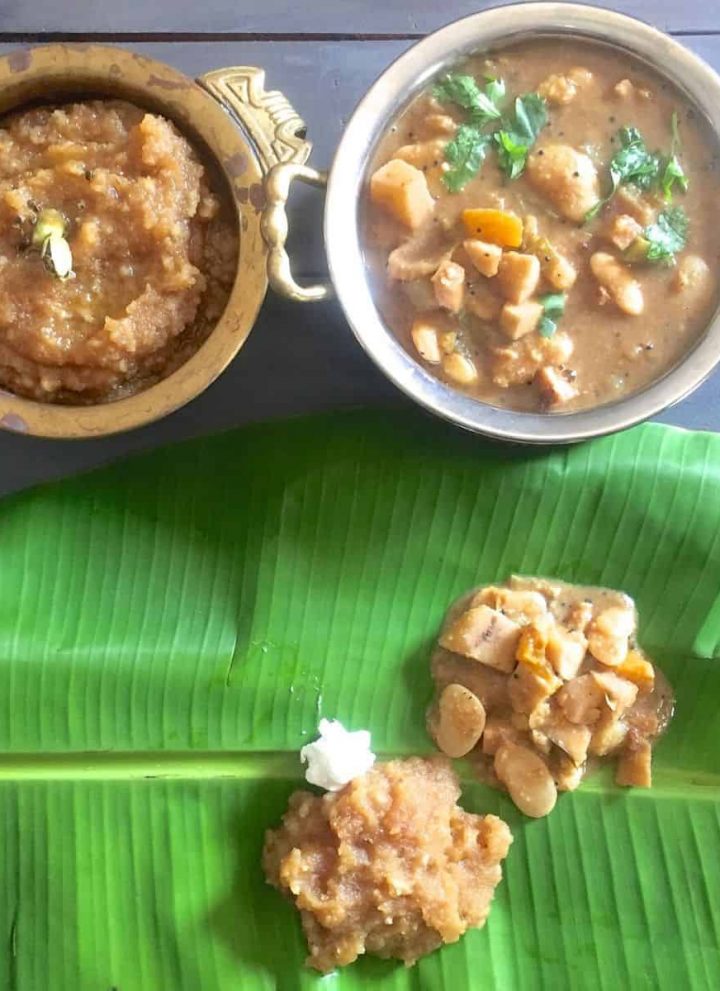 Thiruvathirai Kali, a brown coloured sweet dish, in a brass bowl and some spread on a green banana leaf. Vegetable stew in another bowl and on the leaft, with a pat of white butter by the side