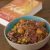 Sauteed Cabbage Potato Peas curry in a brown bowl that is blue inside. A book on emperor Ashoka in the background, all on a brown background