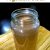 A tall glass jar filled with clear pale brown liquid. Homemade basic vegetable stock on a yellow and brown striped napkin